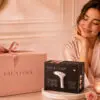 Woman beside FAUSTINA gift packaging and the FAUSTINA 3-in-1 IPL device box